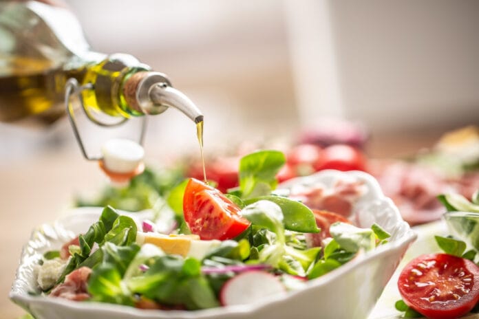 bottle-with-olive-oil-pouring-into-salad