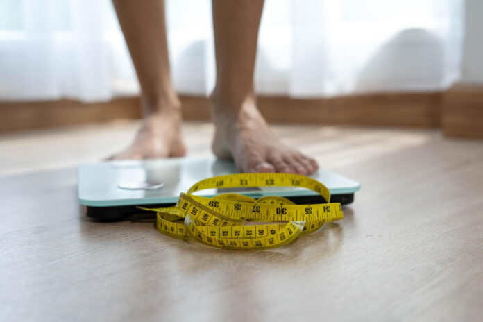 women-stand-electronic-scales-with-measuring-cables-requiring-weight-control-woman-foot-stepping-weigh-scales-with-tape-measure-diet-concept